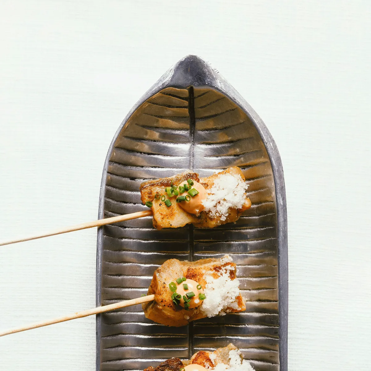 Brochetas glaseadas sobre bandeja artesanal